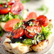 Pesto chicken bruschetta with cherry tomatoes, basil and mozzarella cheese nuts on a plate