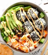 California Sushi Bowl with black sesame seeds, spicy mayo and chopsticks nearby