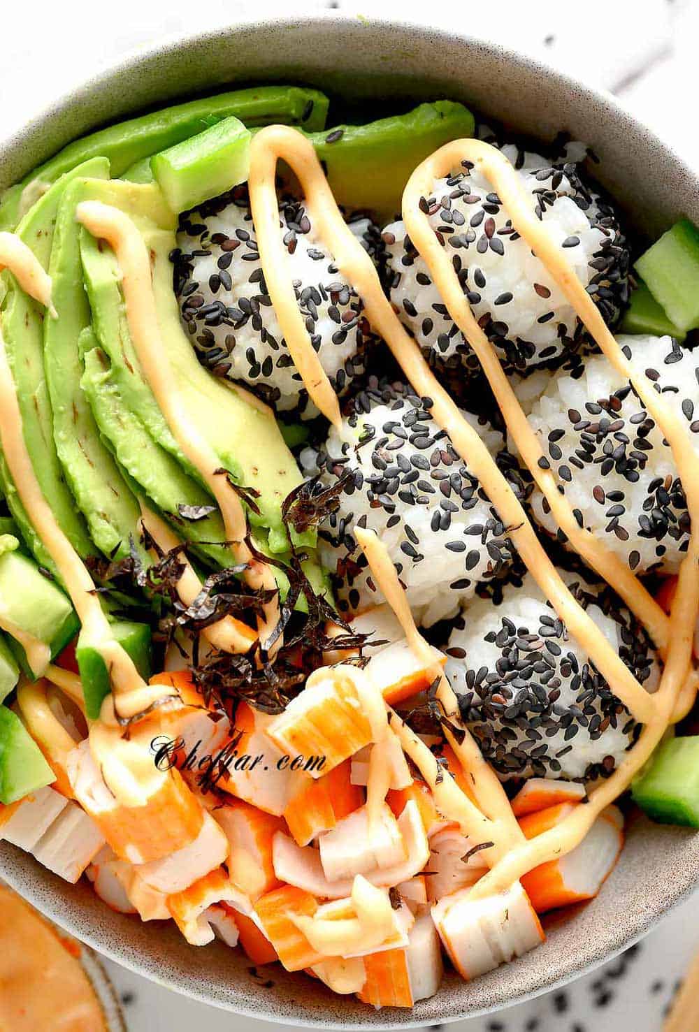 California Sushi Bowl with black sesame seeds, spicy mayo and chopsticks nearby