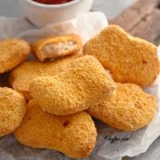 Chicken nuggets on a wooden board lined with parchment papper, served with ketchup. / Air fryer chicken nuggets are absolute perfection! They are crispy on the outside, tender on the inside, and are just waiting to be dipped in your favourite sauce! #airfryer #airfryerrecipes #chicken