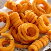 air fried curly fries on the board lined with parchment paper
