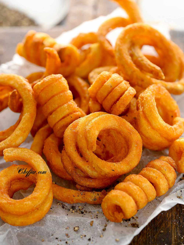air fried curly fries on the board lined with parchment paper