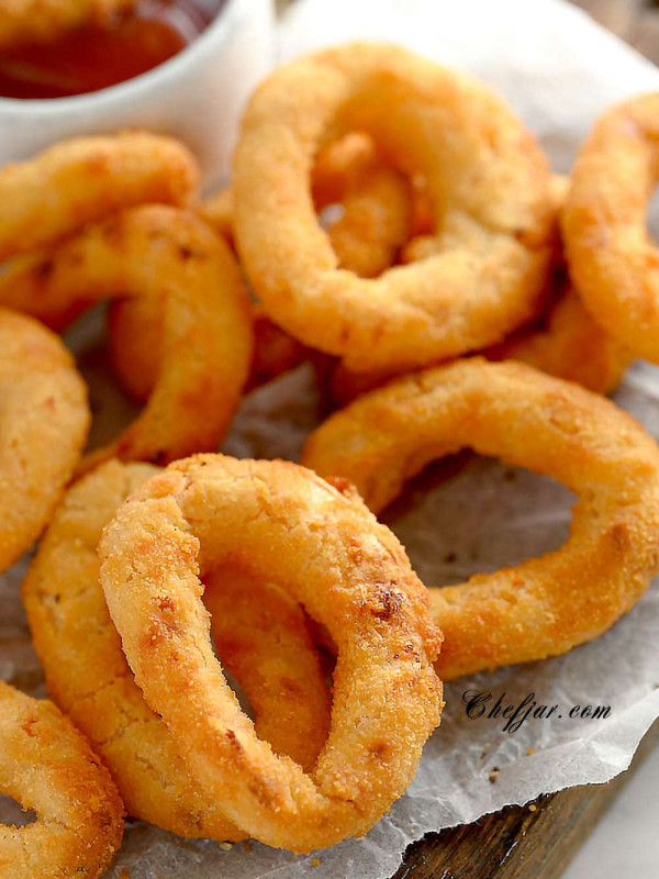 air fried onion rings on a board lined with parchment paper