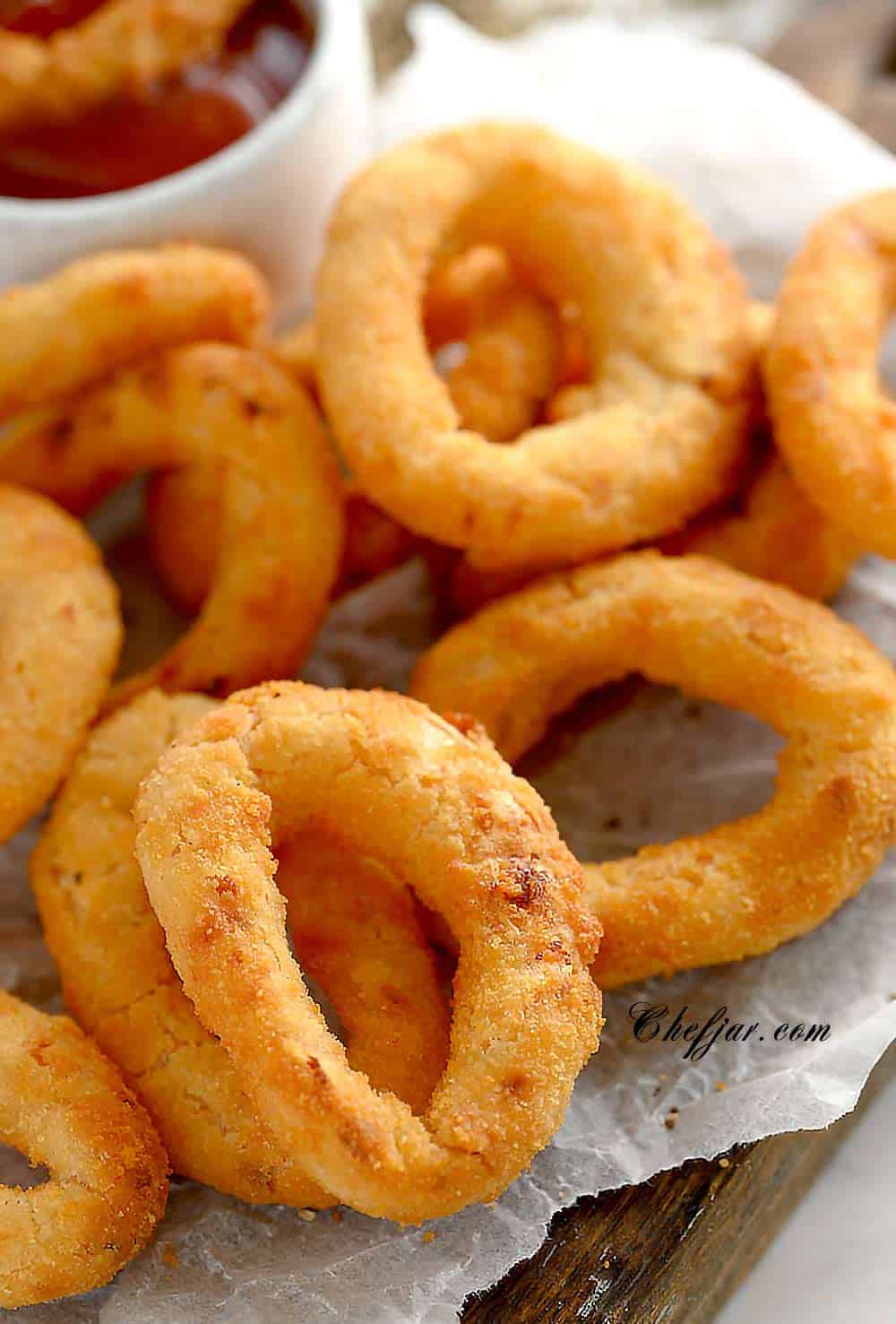 air fried onion rings on a board lined with parchment paper