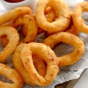 air fried onion rings on a board lined with parchment paper