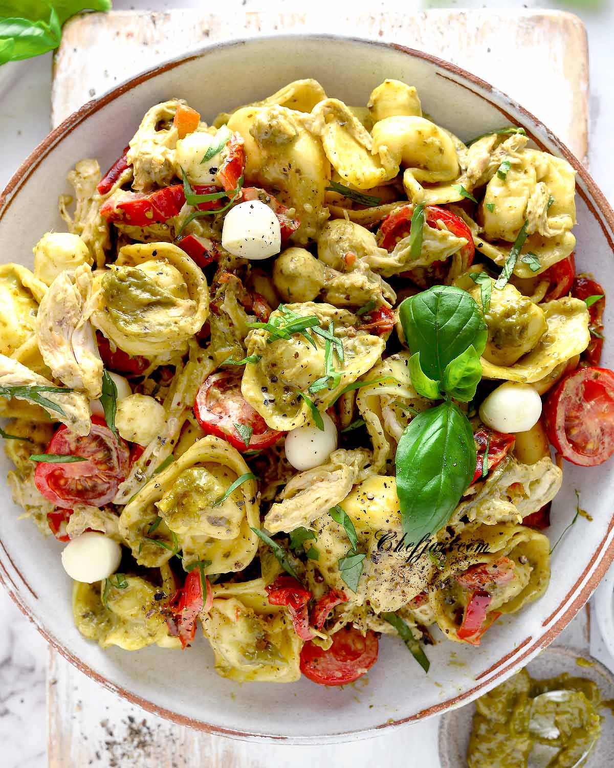 pesto tortellini salad served in a white bowl