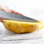Cutting board with large potato being cut