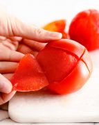 How to peel and seed a tomato - showing peeled tomato on white cutting board /