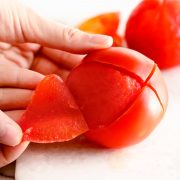 How to peel and seed a tomato - showing peeled tomato on white cutting board /