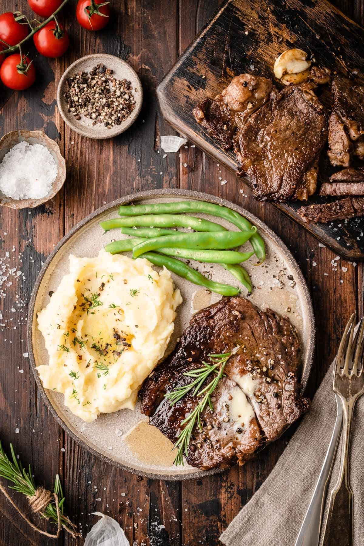 An overhead shot of the plate with pan seared wagyu ribeye steaks served with mashed potatoes and roasted green beans.