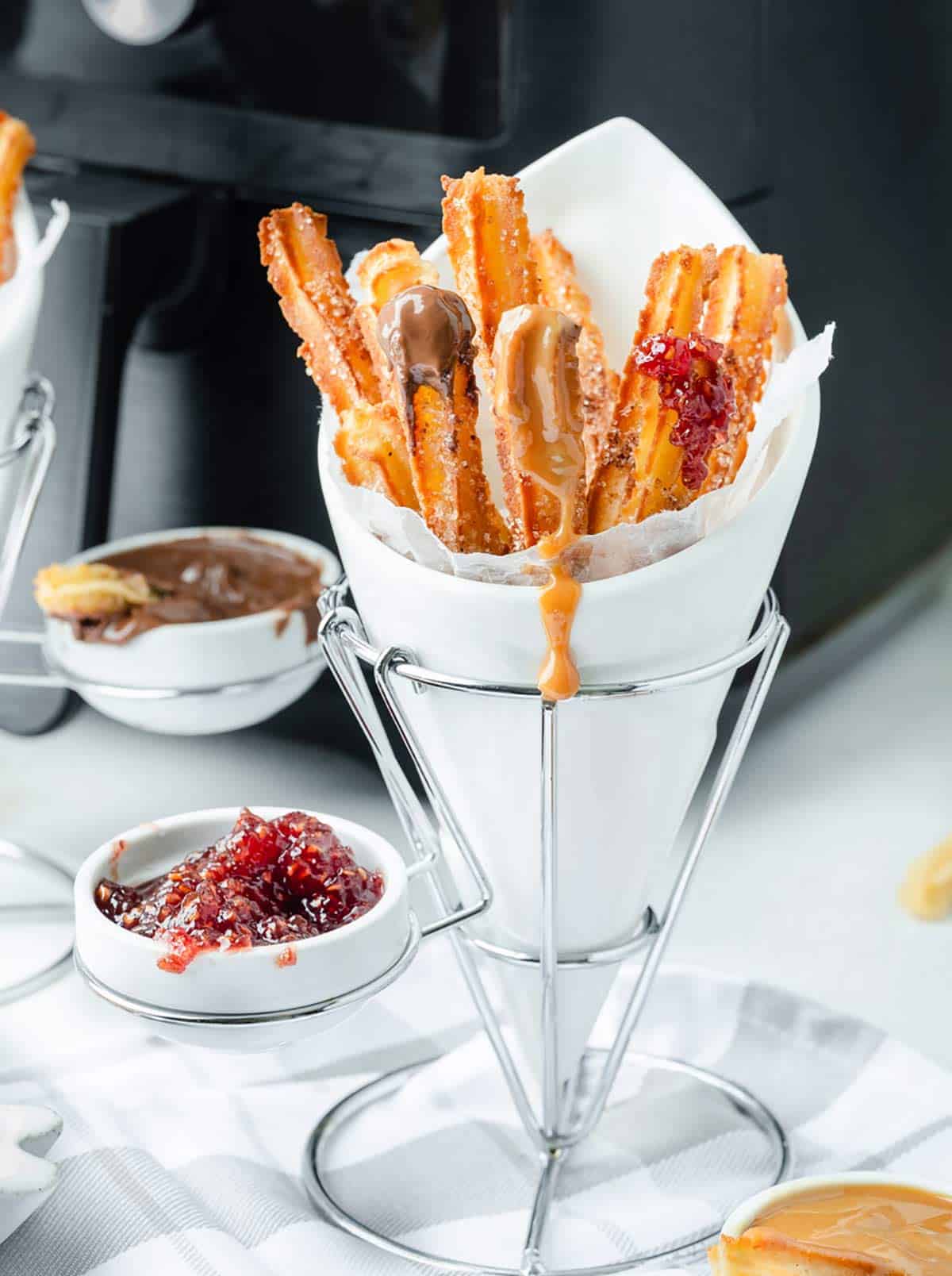Crispy air fryer churros with cinnamon sugar. Served with dulce de leche, Nutella and jam.