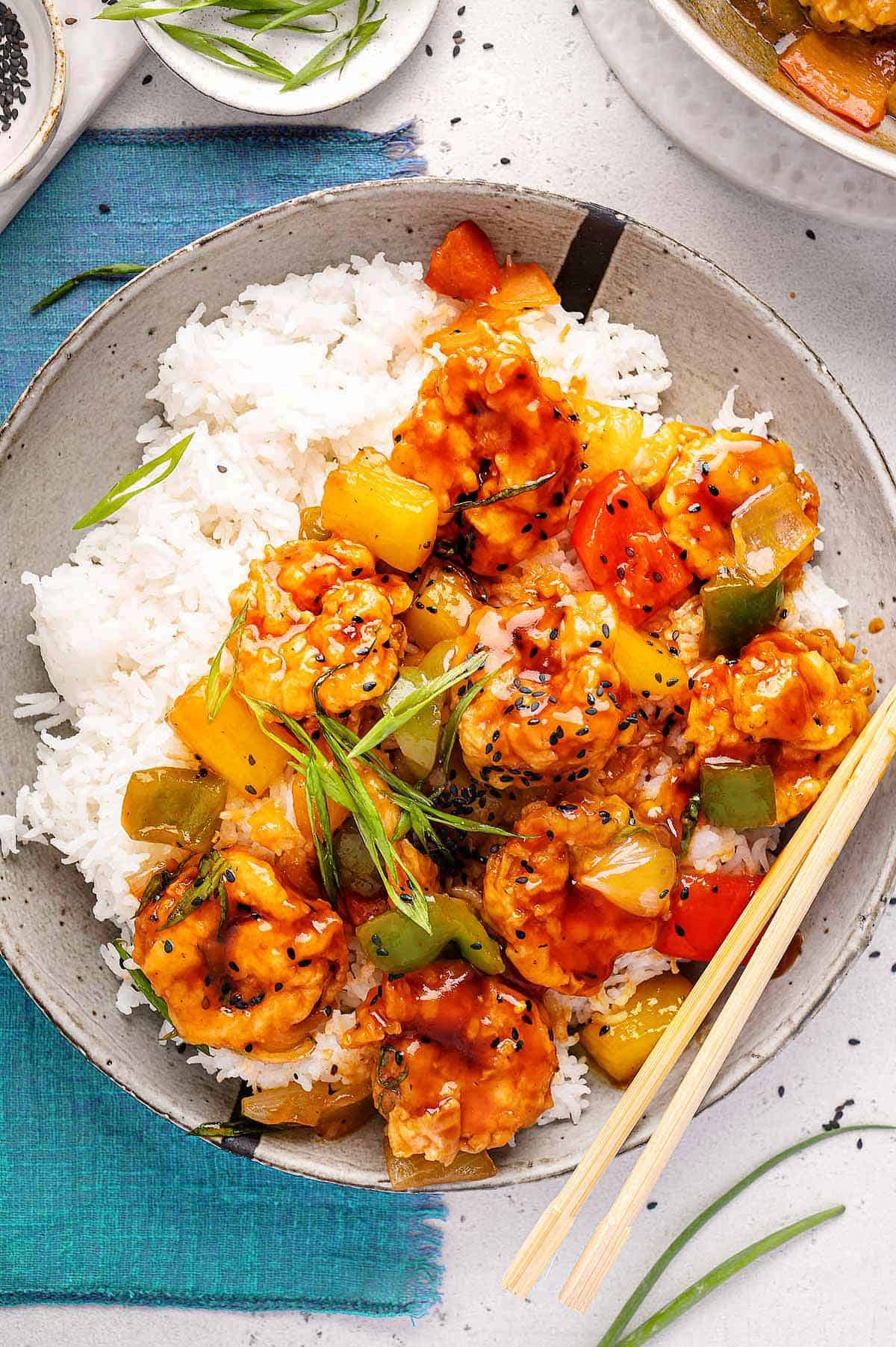 An overhead image of the sweet and sour prawns served on a white plate with steamed rice.