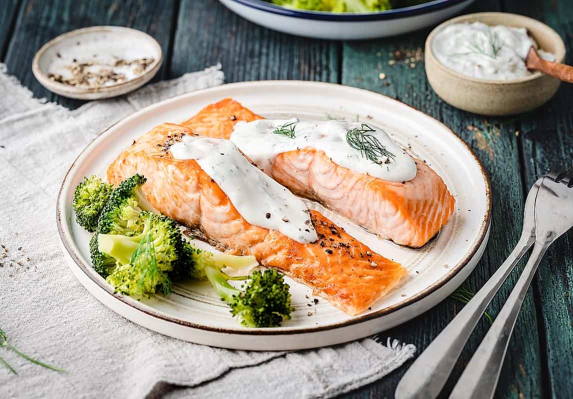 Air Fryer Salmon with Creamy Dill Sauce in background 