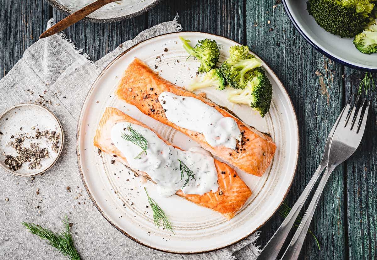 An overhead  image of a plate with air fried salmon topped with creamy dill sauce.