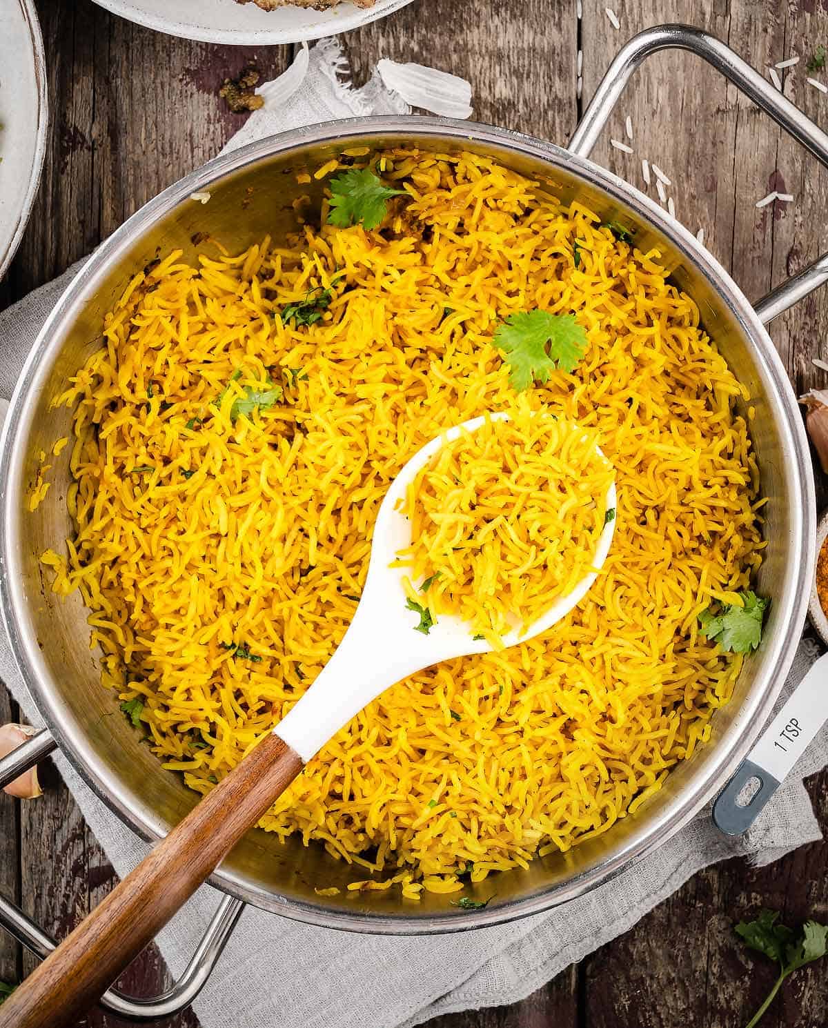 An overhead shot of the pot of turmeric rice with fresh cilantro leaves
