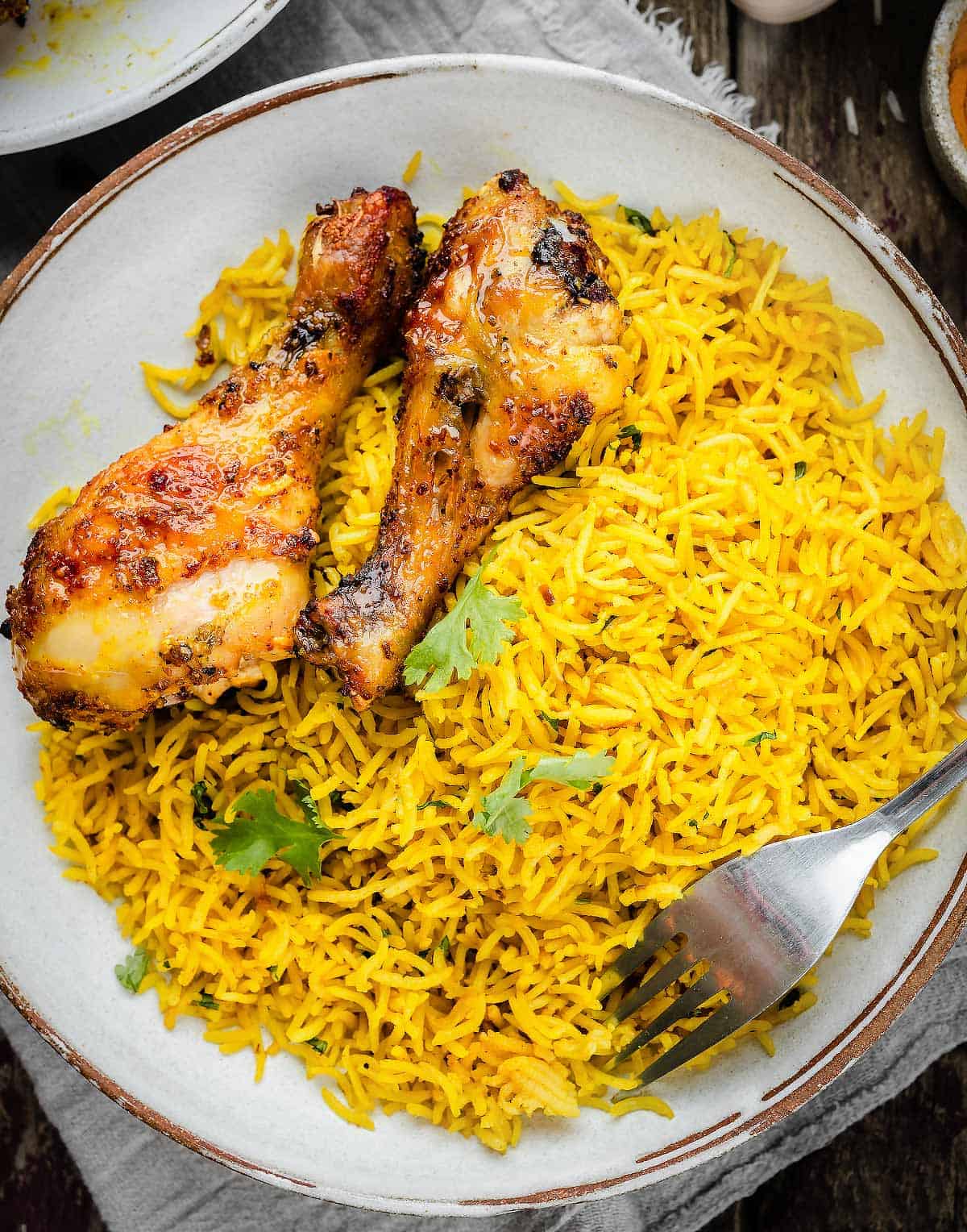 Garlic Turmeric rice served in a bowl with chicken drumsticks