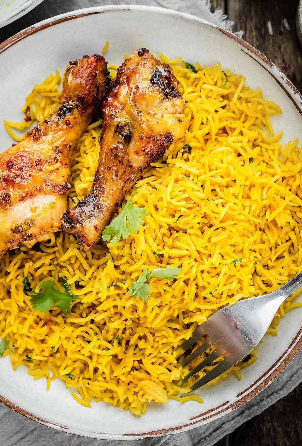Garlic Turmeric Rice in a bowl/ served with chicken drumsticks