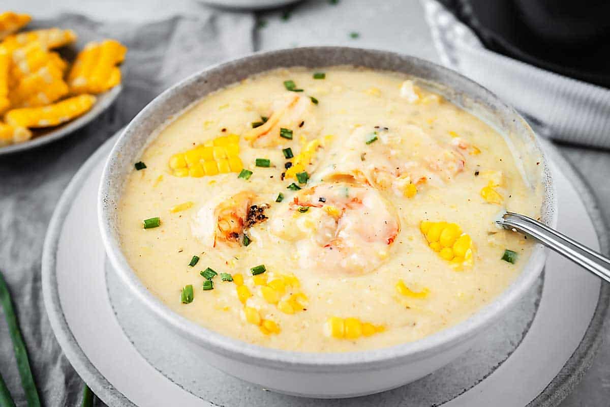 Angle view of a white bowl with shrimp and corn soup 