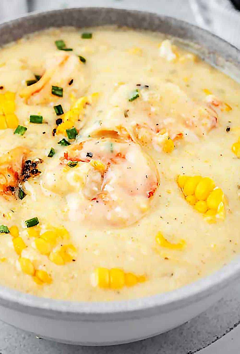 Overhead view of a white bowl with shrimp and corn soup