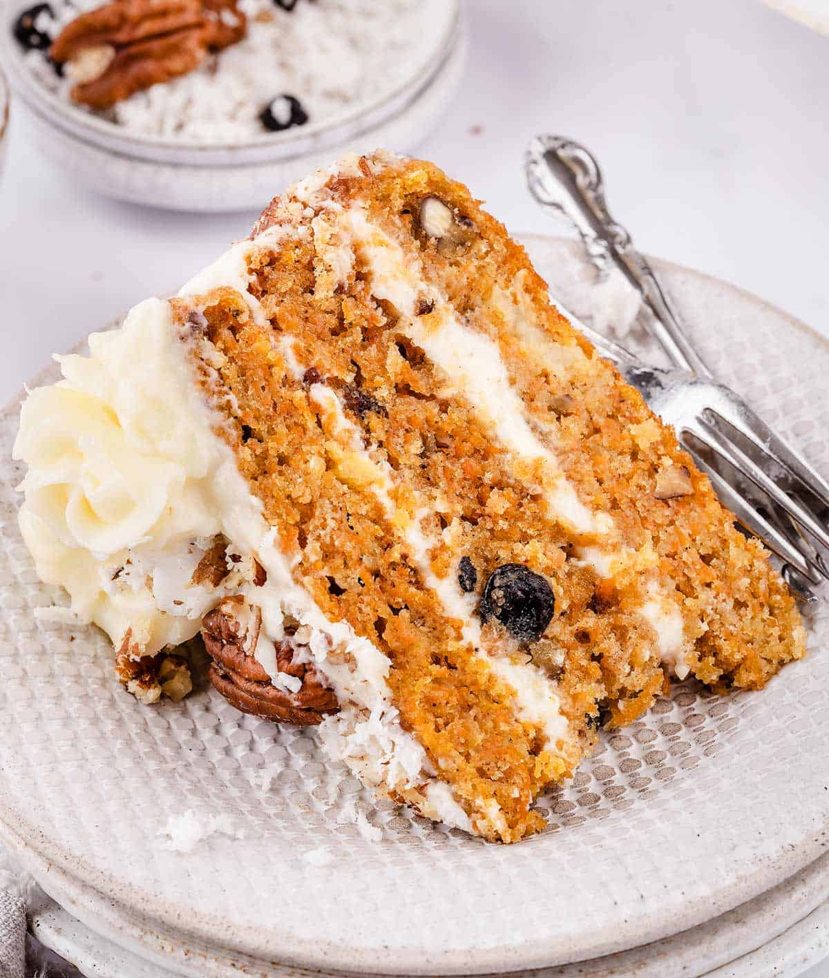 A slice of carrot cake with pineapple and coconut on a plate. 	This is my favorite recipe for homemade carrot cake.