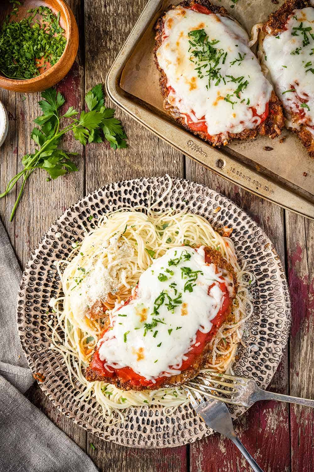 Chicken parmesan and spaghetti on a dinner plate.