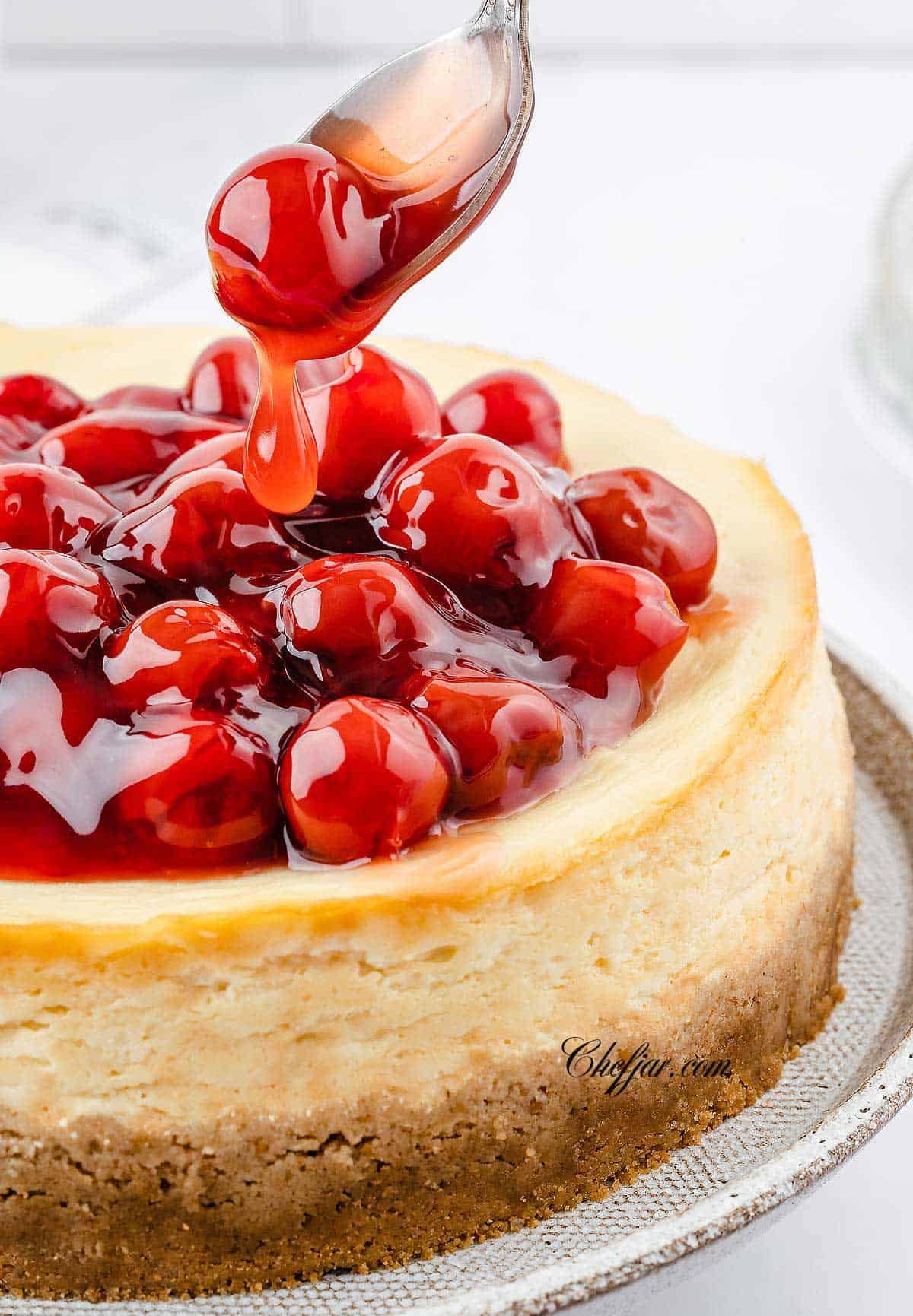 Pouring cherry sauce over the cheesecake.