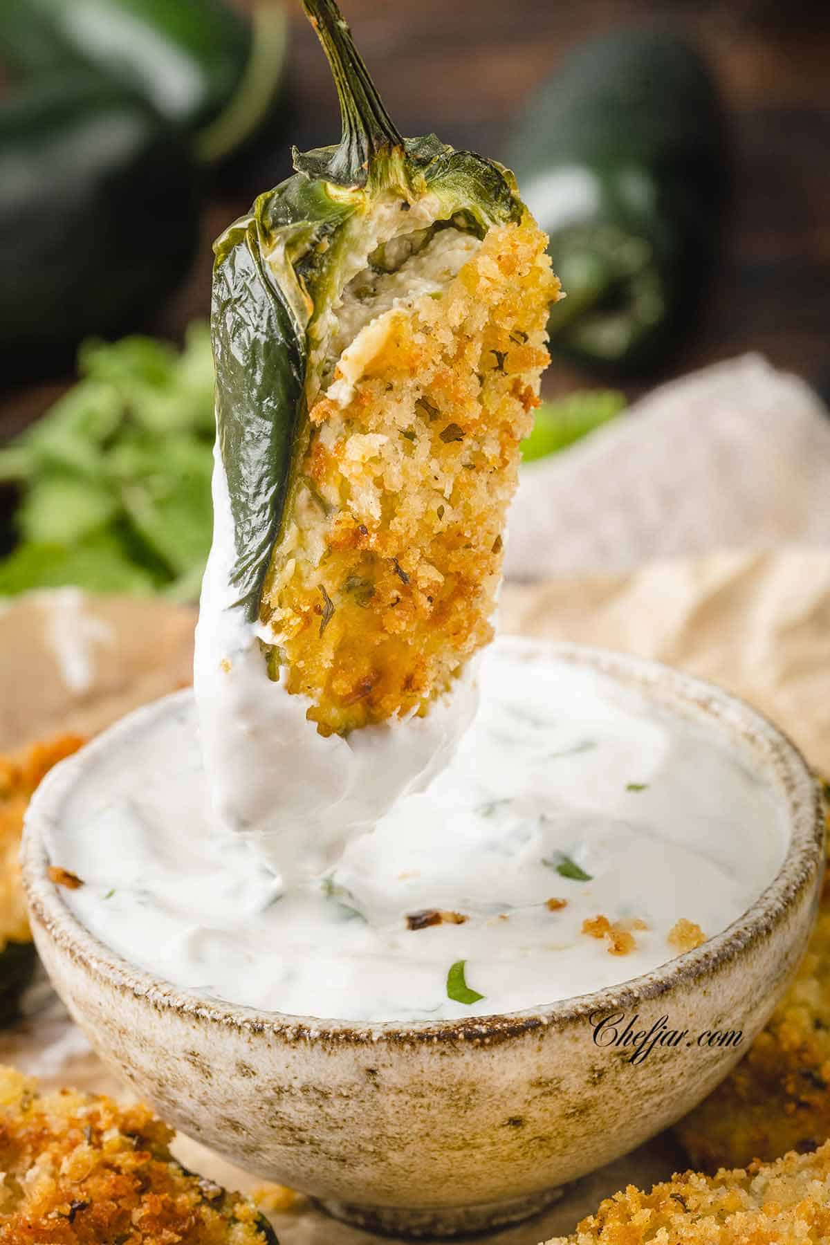 Dipping an air fried jalapeno pepper in a sour cream dip.