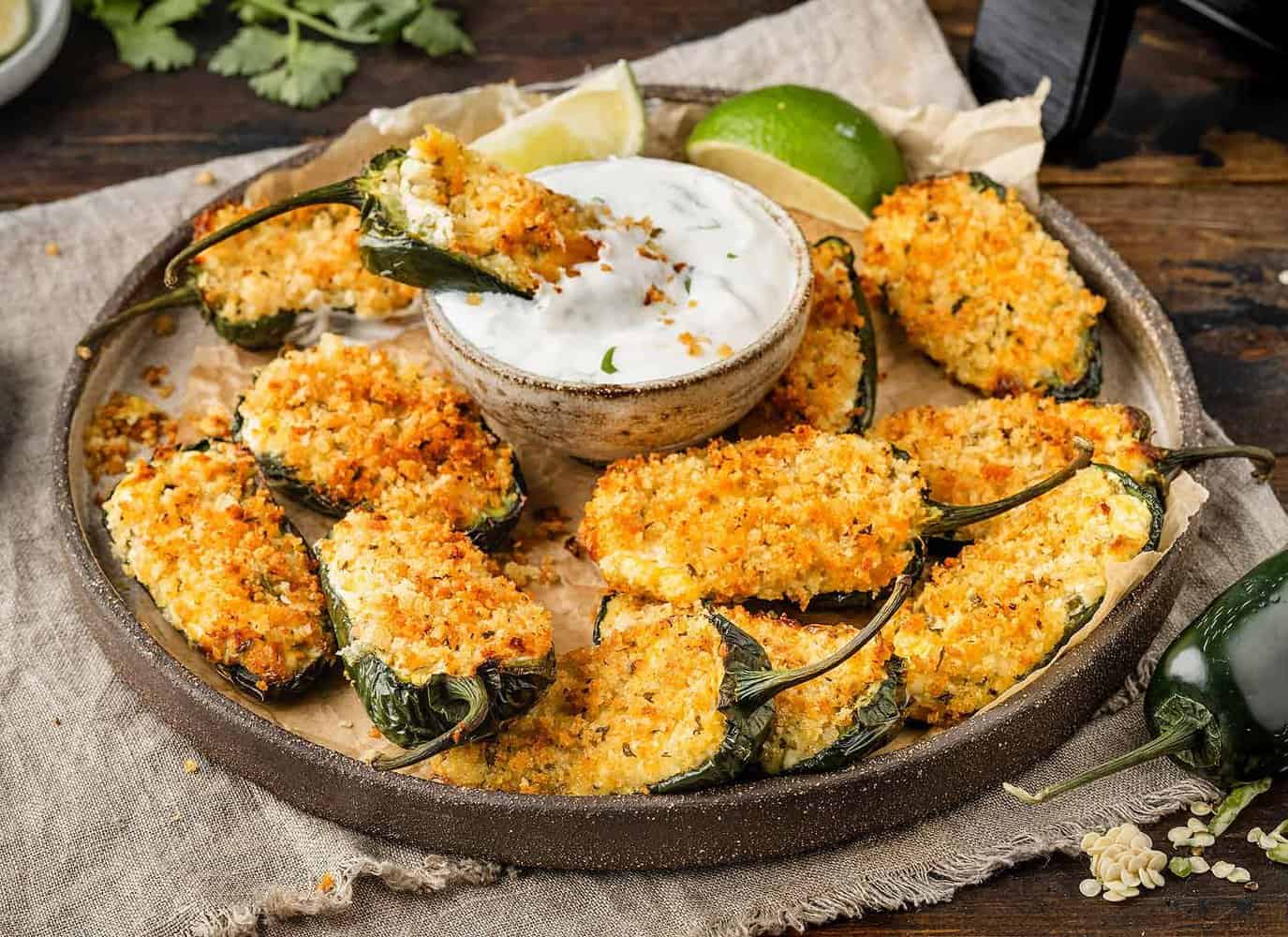 A plate of Air Fryer Jalapeño Poppers with sour cream dip and air fryer in the background.