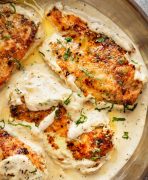 A close up image of Herb Chicken in a cream sauce with fresh parsley and rosemary./