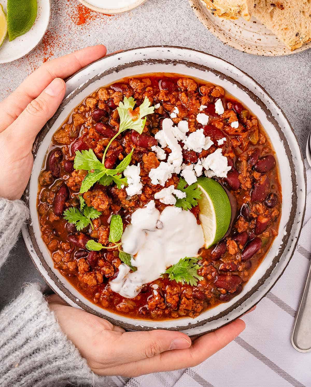 Hands holding a bowl of homemade lamb chili.