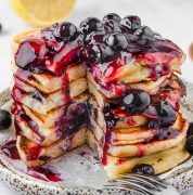 A stack of ricotta pancakes topped with blueberry sauce with a bite cut / Lemon Blueberry and Ricotta Pancakes
