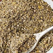 An image of Lemon Pepper Seasoning in a small white bowl, with a silver spoon.