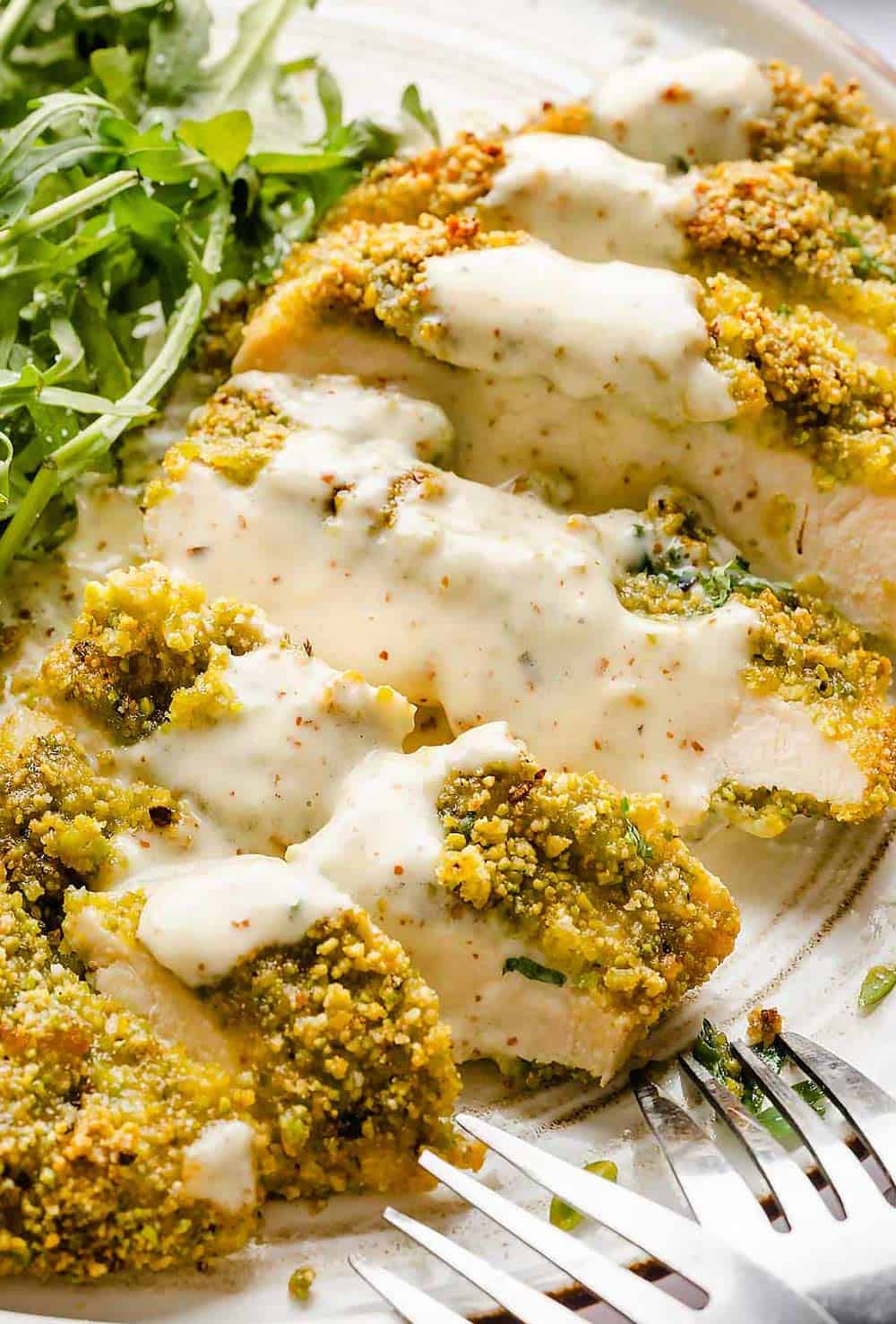 Sliced pistachio crusted chicken on plate with honey garlic sauce/ Pistachio Crusted Chicken