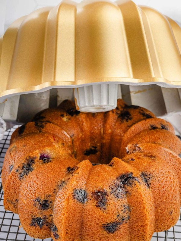 Flipping the bundt cake upside down onto a wire rack to cool, allowing gravity to help release it from the pan.