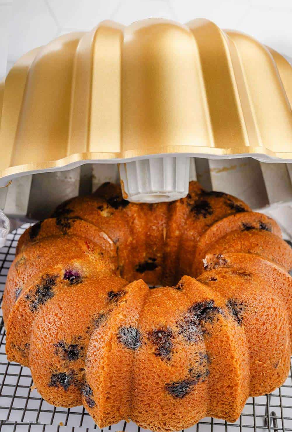 Flipping the bundt cake upside down onto a wire rack to cool, allowing gravity to help release it from the pan.