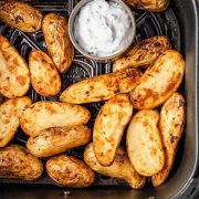 Roasted fingerling potatoes in an air fryer basket, seasoned with salt and lemon pepper seasoning.