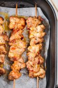 Top view of three golden-brown Lemon Pepper Chicken Skewers cooked in an air fryer basket, with a crisp exterior and juicy interior.