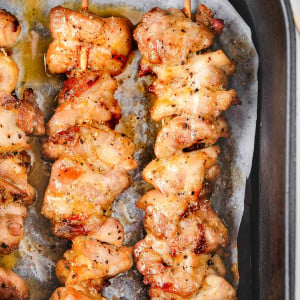 Top view of three golden-brown Lemon Pepper Chicken Skewers cooked in an air fryer basket, with a crisp exterior and juicy interior.
