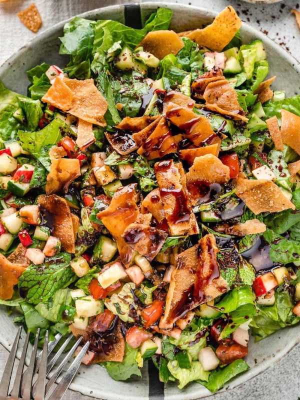 Fattoush Salad served in a large grey bowl, topped with crispy pita bread chips and drizzled with sweet and tangy pomegranate molasses dressing.