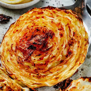 A cooked cabbage steak being lifted with a spatula, revealing its golden-brown crispy outer layer and tender inside, ready to be served.