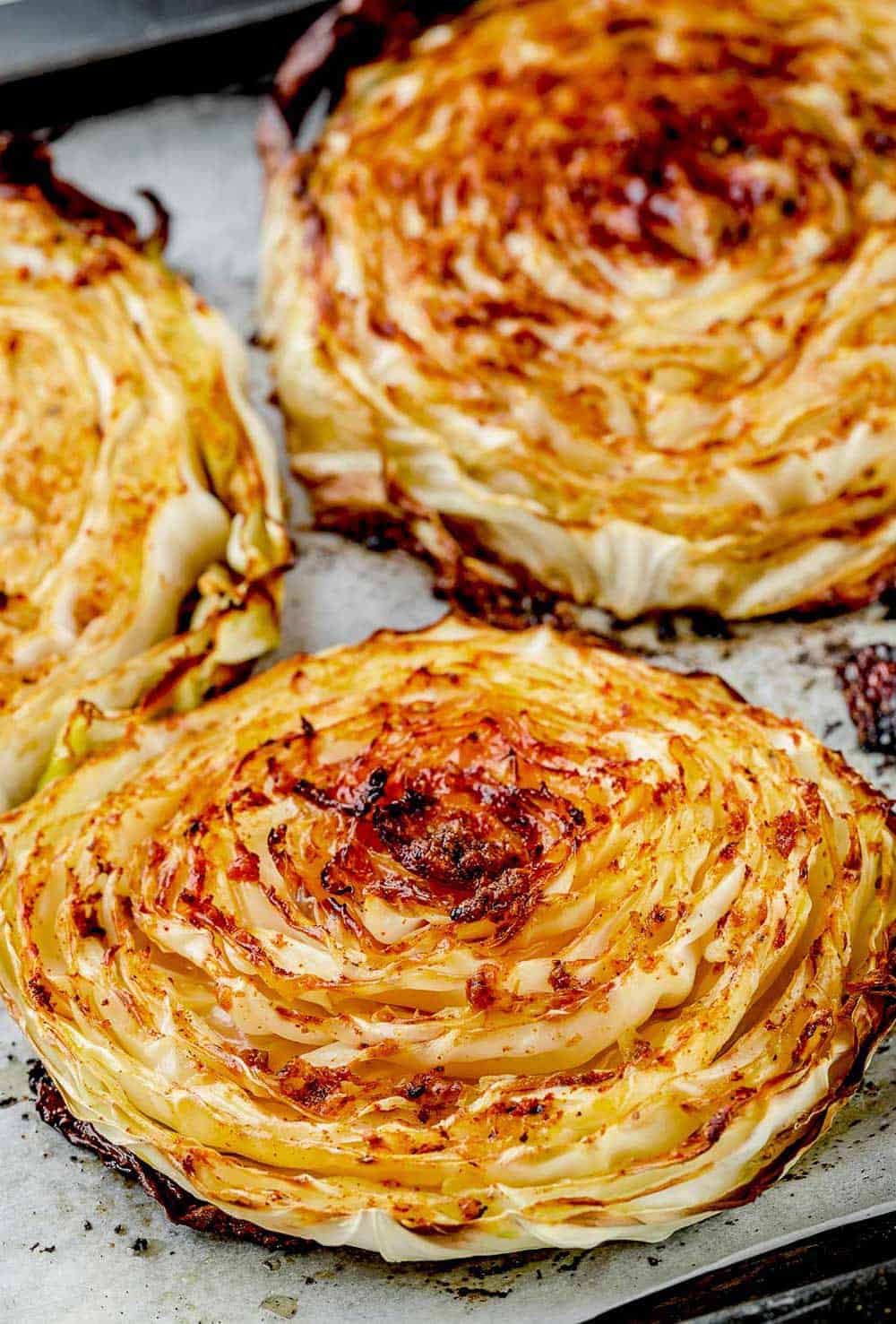 Golden-brown roasted cabbage steaks on a baking sheet, cooked to perfection with a crispy outer layer and tender inside.
