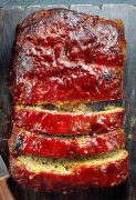 A sliced meatloaf on the wooden cutting board.