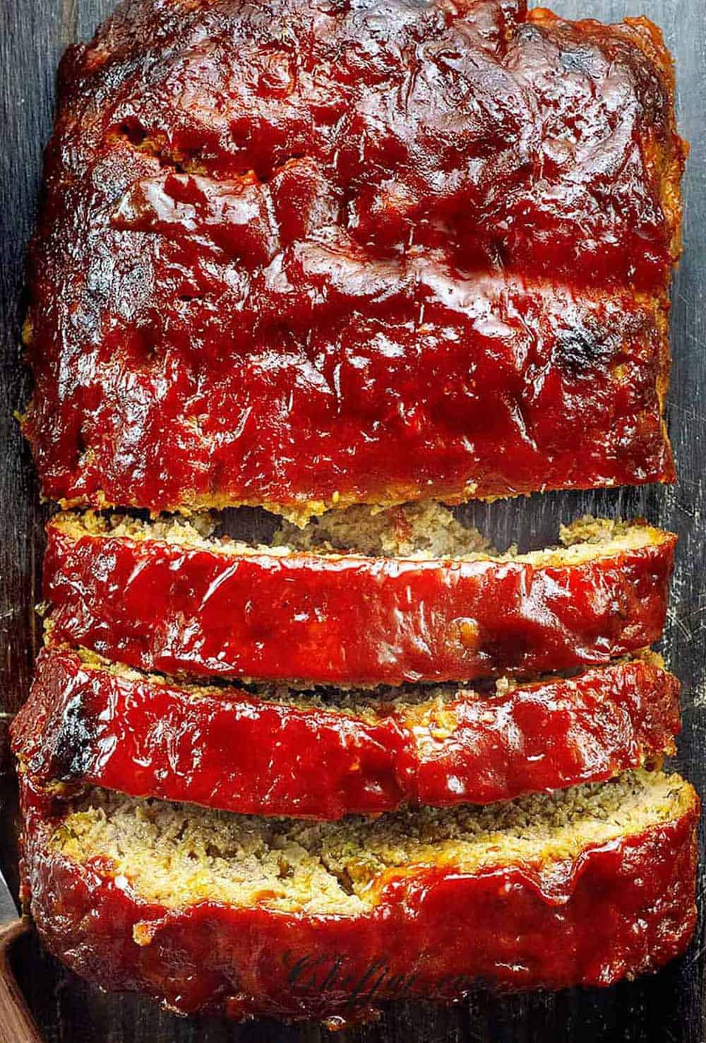 A sliced meatloaf on the wooden cutting board.