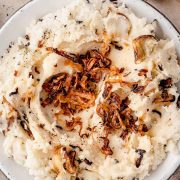 Fluffy caramelized shallot mashed potatoes served in a bowl, topped with crispy shallots.