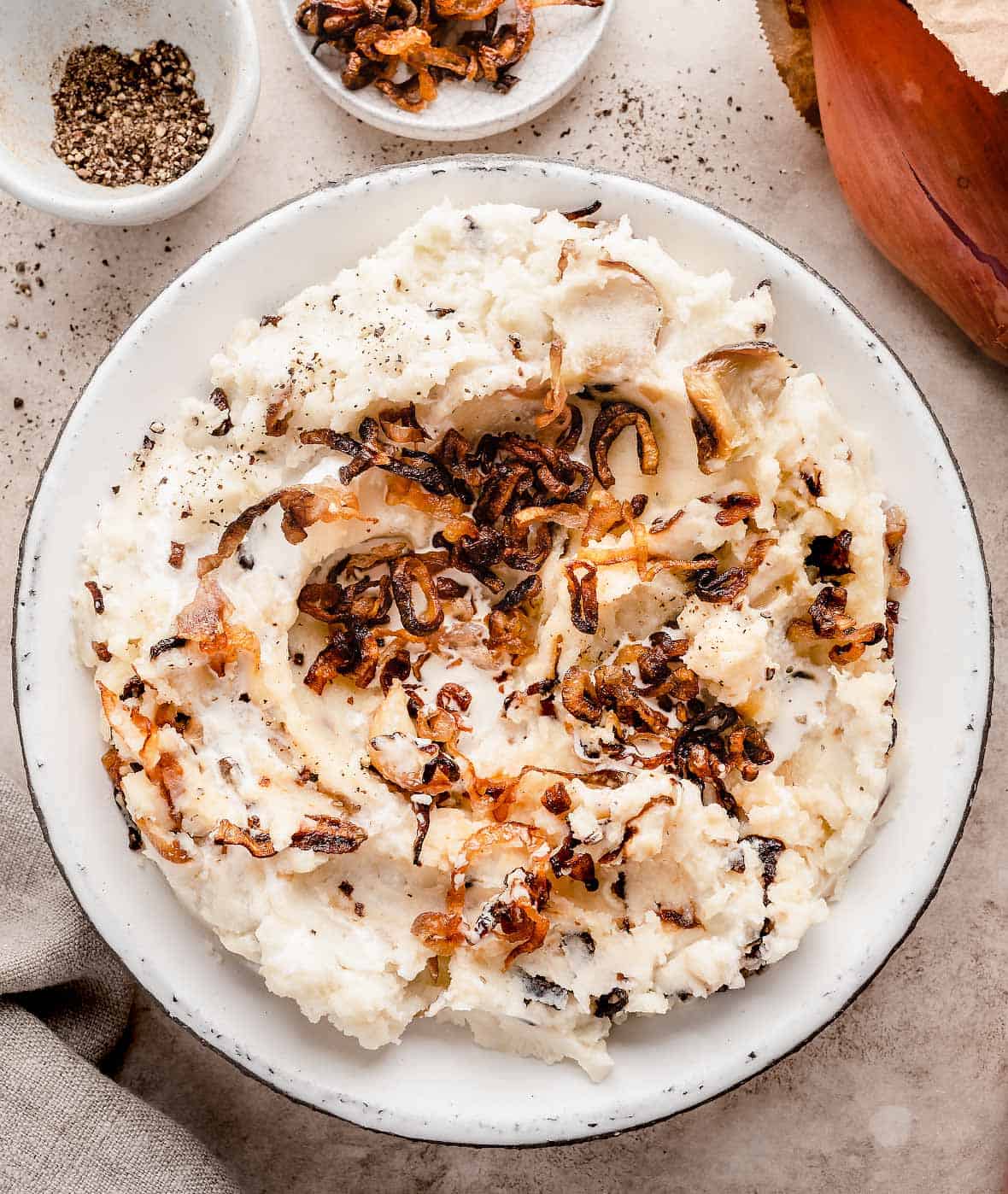 Fluffy caramelized shallot mashed potatoes served in a bowl, topped with crispy shallots.