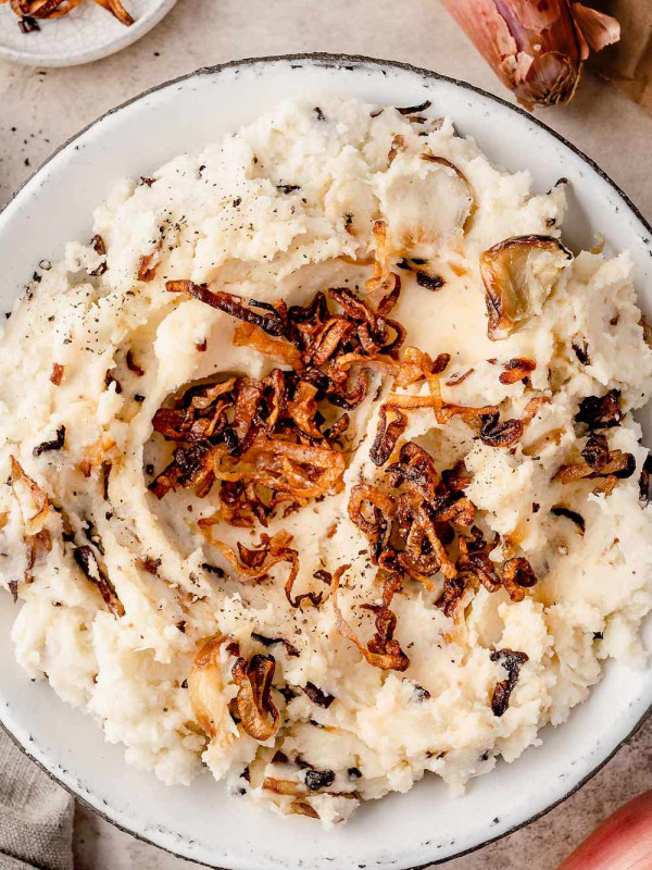 Fluffy caramelized shallot mashed potatoes served in a bowl, topped with crispy shallots.