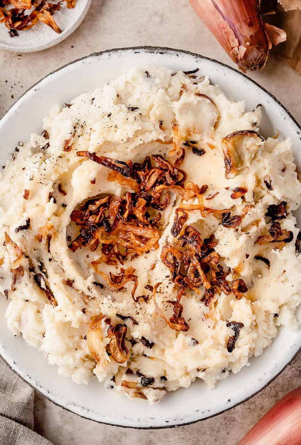 Fluffy caramelized shallot mashed potatoes served in a bowl, topped with crispy shallots.