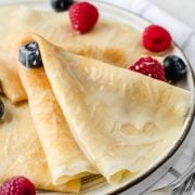 Close-up view of crepes drizzled with condensed milk with blueberries and raspberries.