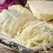 Image of finely shredded cabbage, with thin and uniform slices of pale green leaves arranged in a pile.