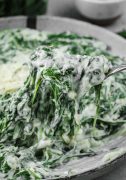 Steakhouse creamed spinach, a rich and creamy side dish, being lifted with a fork.